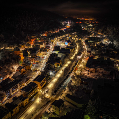 Winterlich-verschneit und hell erleuchtet: Tarvisio bei Nacht aus der Vogelperspektive
